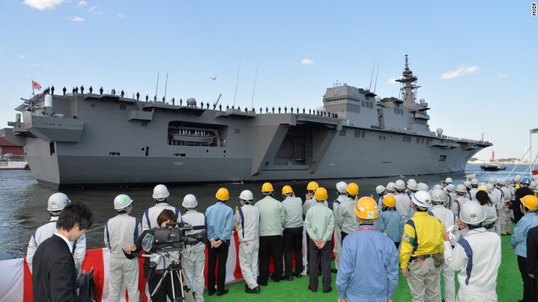 Travailleurs regardent au Japon & # 39; s plus récent - et le plus grand - navire de guerre, Izumo, amarré à Yokosuka, Kanagawa.